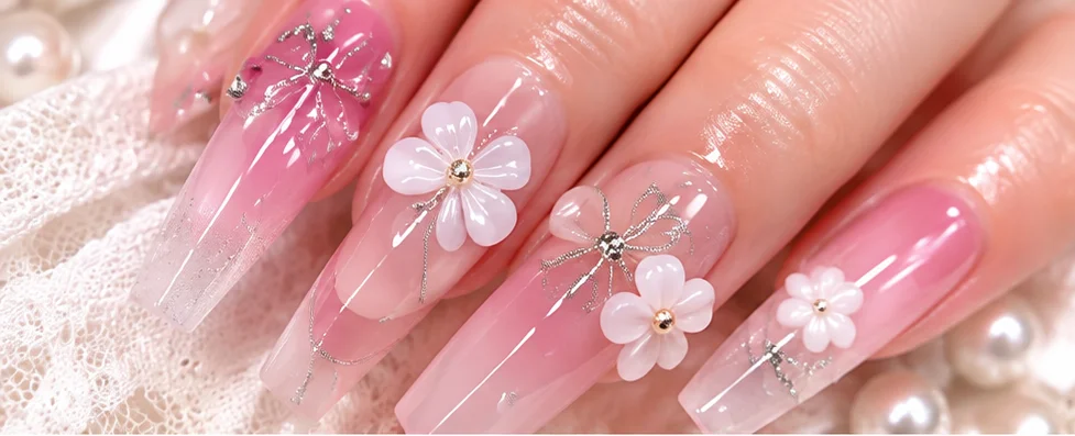 花のパーツとリボンをあしらったピンクのロングネイル